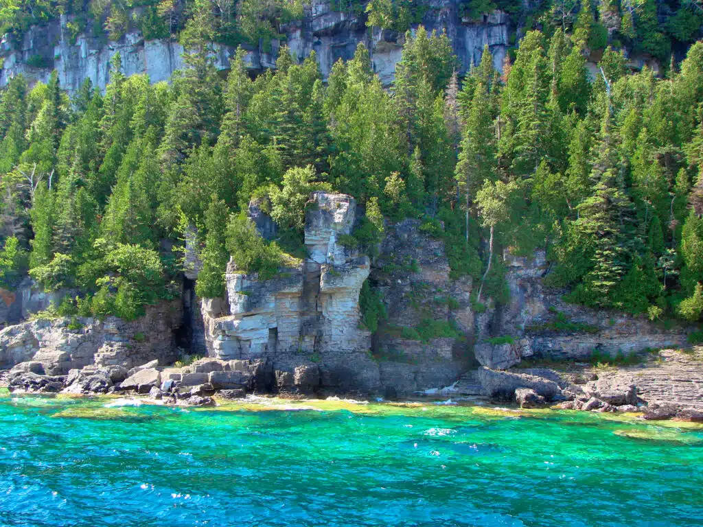 Cliffs with trees above and crystal clear water below in Fathom Five National Marine Park, Tobermory, Ontario